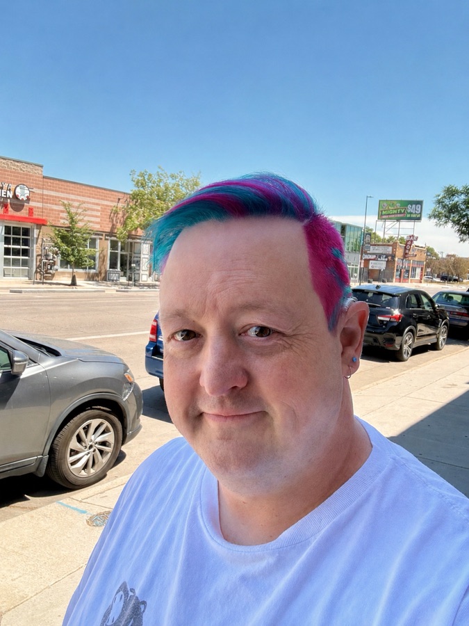 Robee smiling outside with bright blue and magenta hair